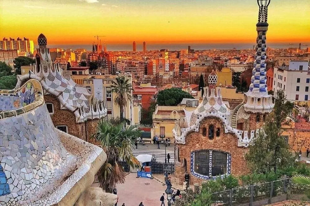 Park Güell's mosaic gatehouses at sunset with the city beyond