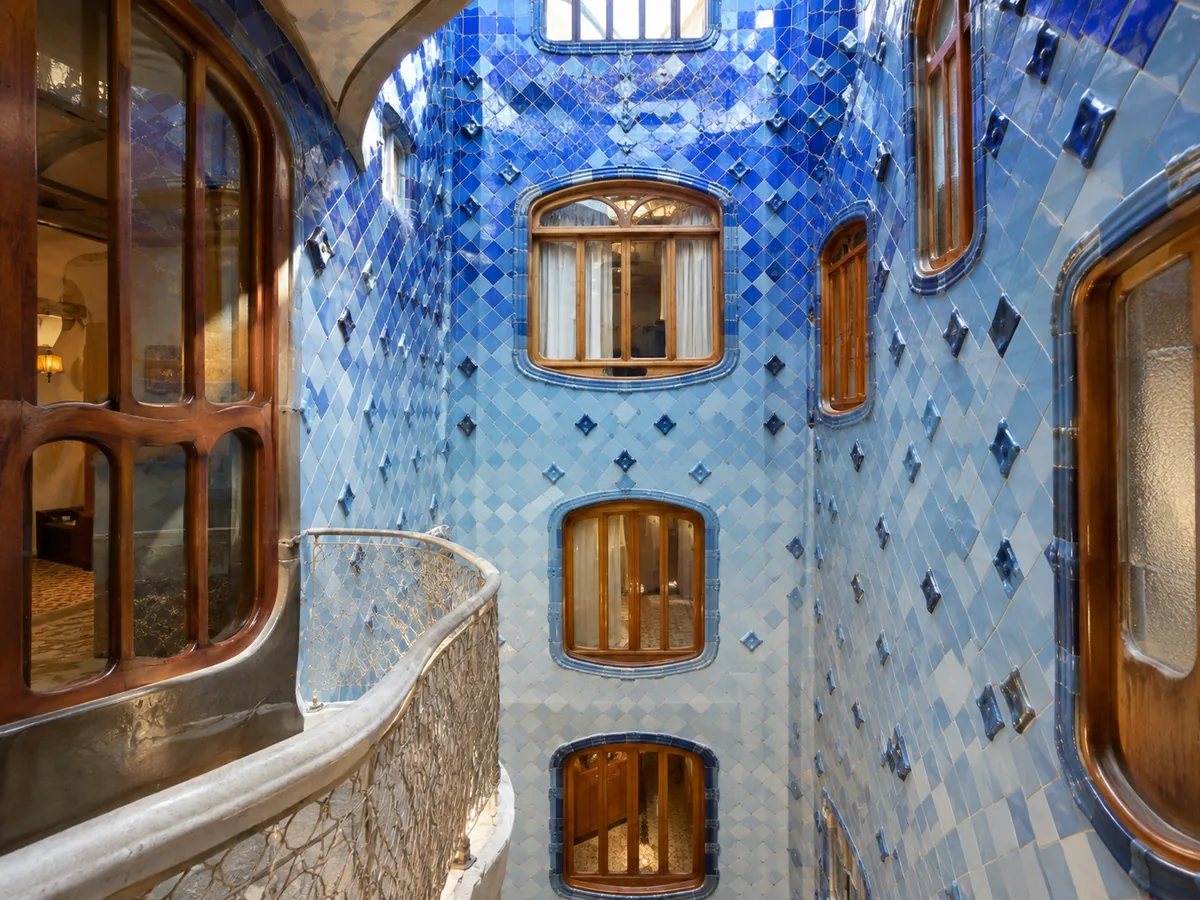 A light well lined with blue ceramic tiles and curving wooden windows